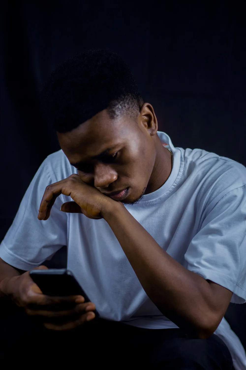 A young man looking thoughtfully at his phone