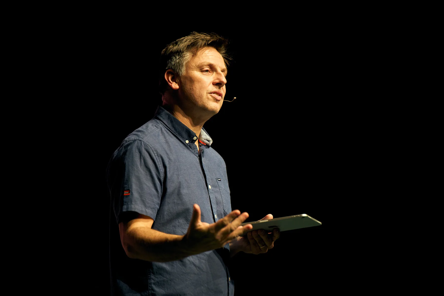 A speaker presenting on stage with a headset microphone
